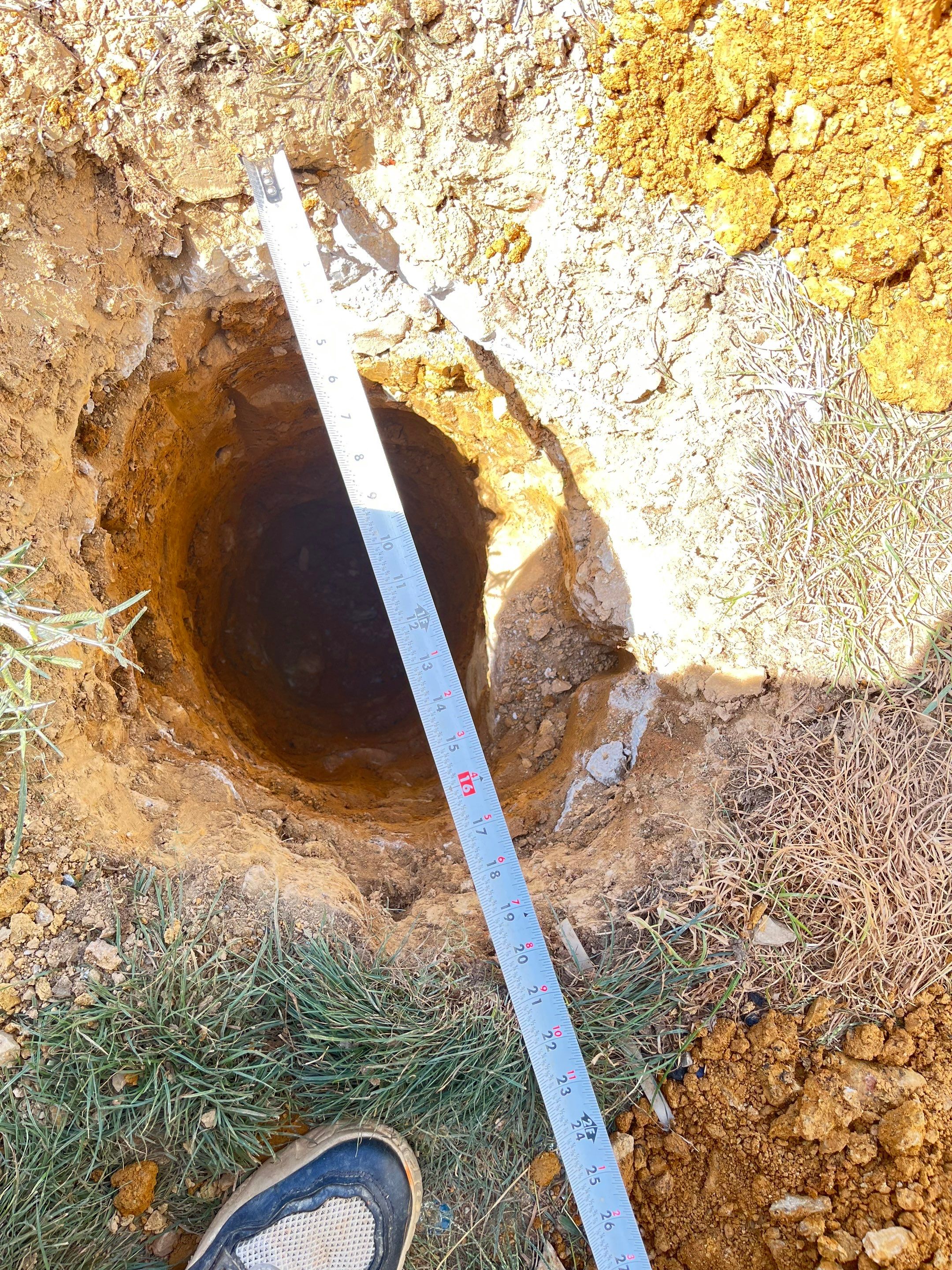 Tape measure checking the depth of a deck footing hole